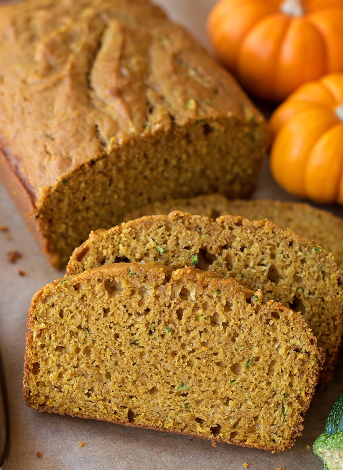 Pumpkin and spice adds a hint of fall to this moist and tender pumpkin zucchini bread. It's easy to make and even easier to customize! Freshly baked pumpkin zucchini bread loaf with slices.