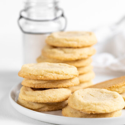 Drop sugar cookies stacked on a white plate.