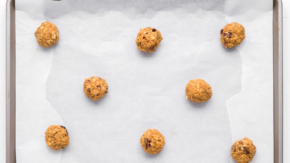 Oatmeal craisin cookie dough rolled into balls on a baking sheet