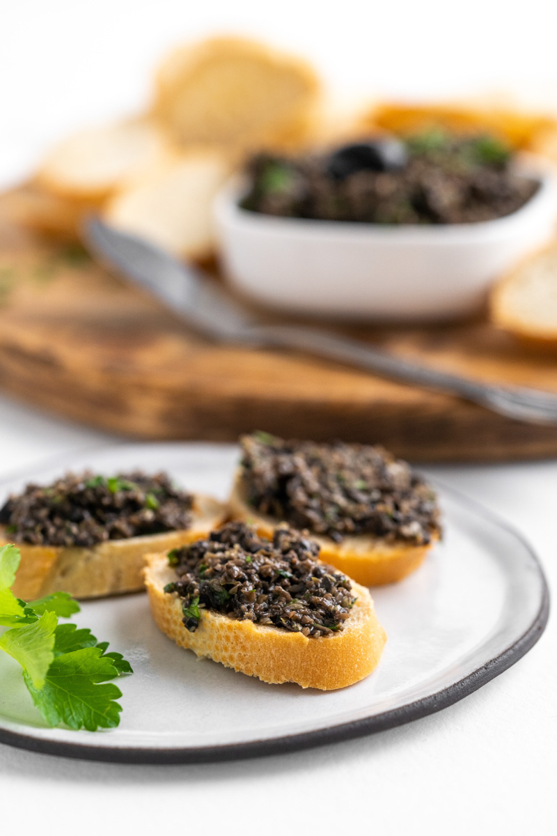 Slices of baguette with black olive tapenade on it 