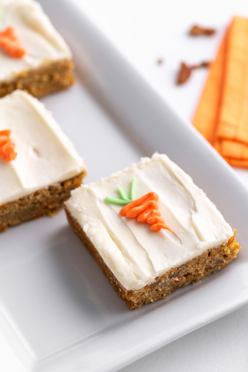 Close up of Carrot cake bars on a white plate.