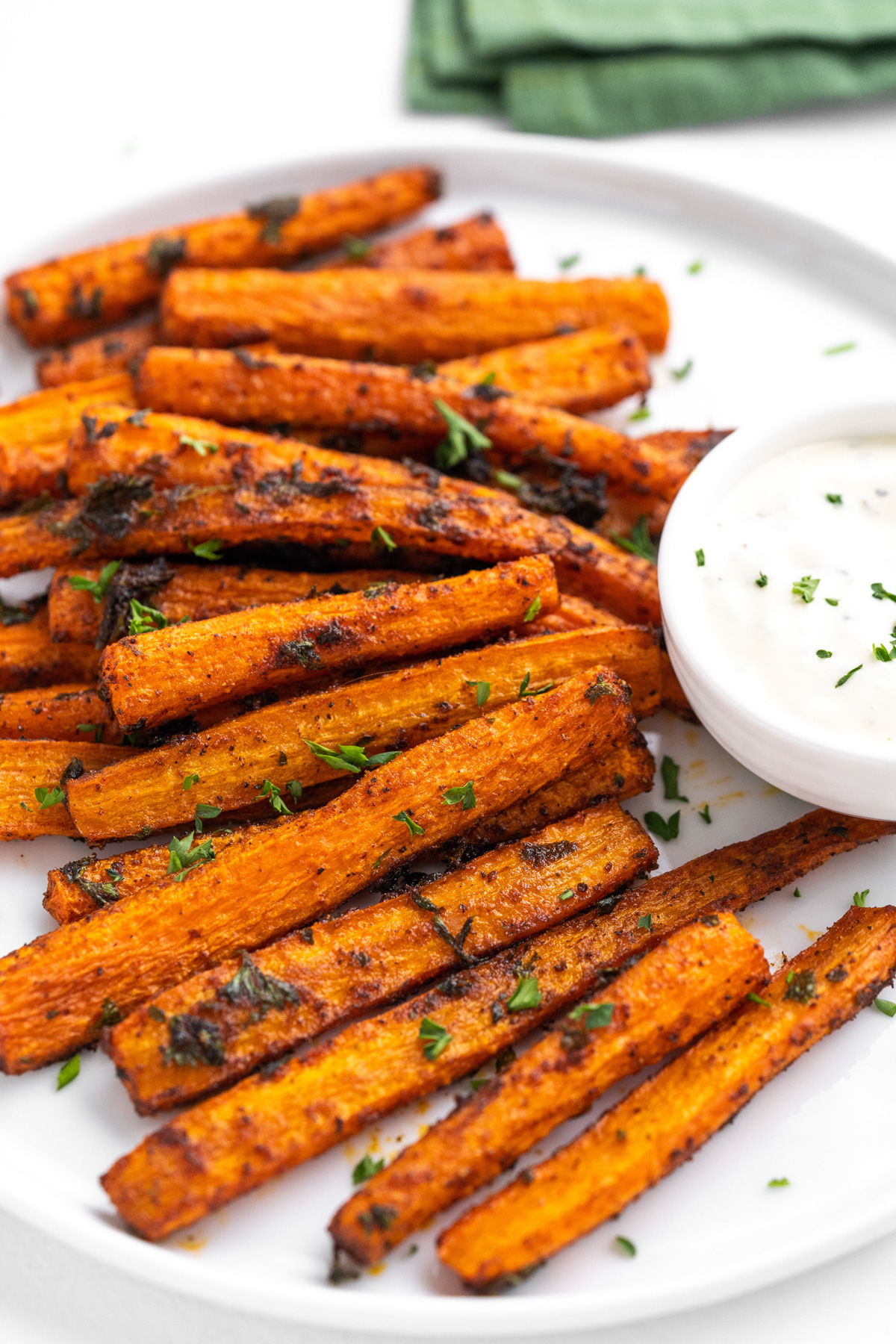 Carrot fries on a white plate with a ramakin of ranch dressing on the side.
