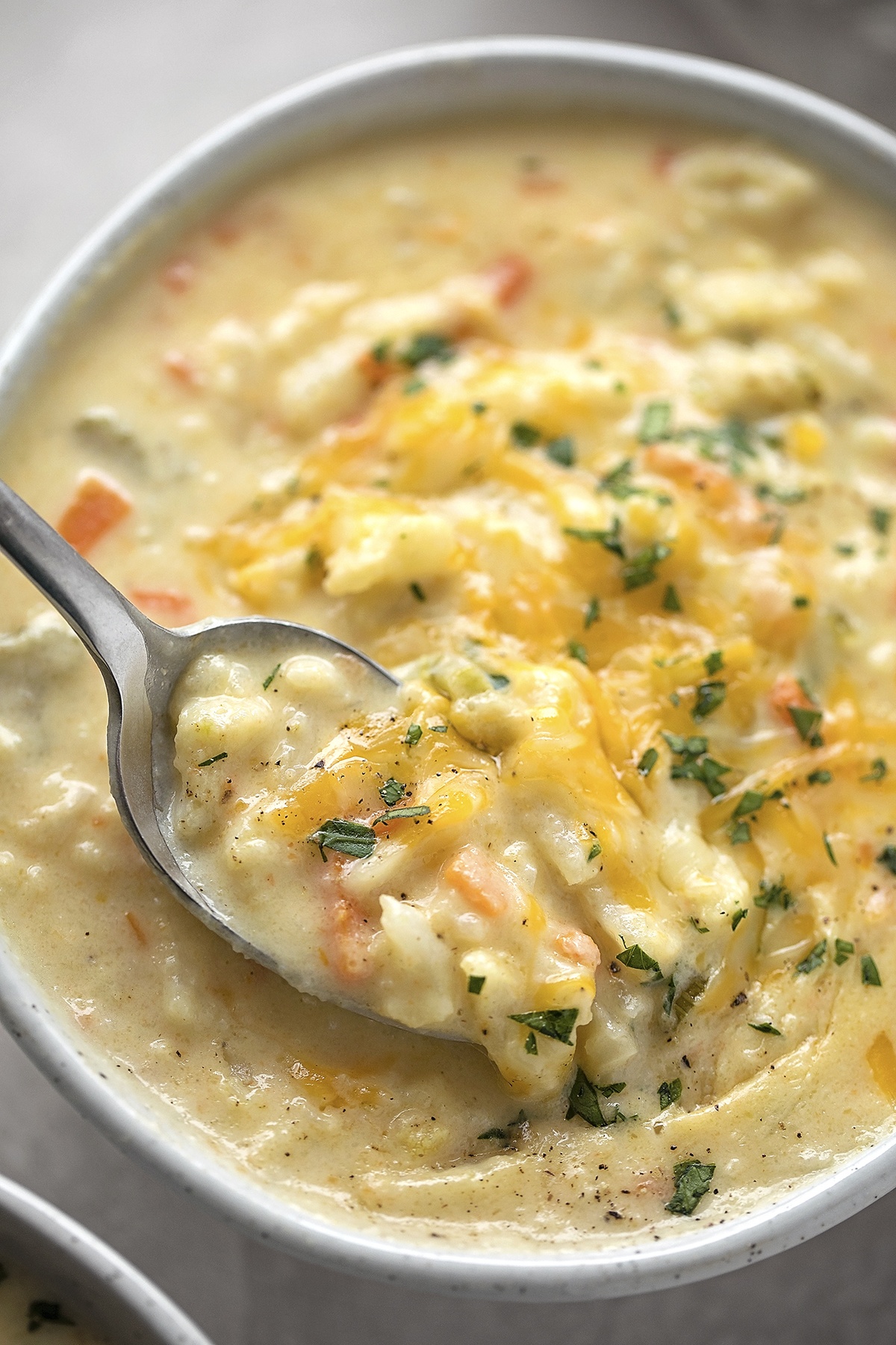 Cheesy cauliflower soup in a bowl, garnished with parsley.