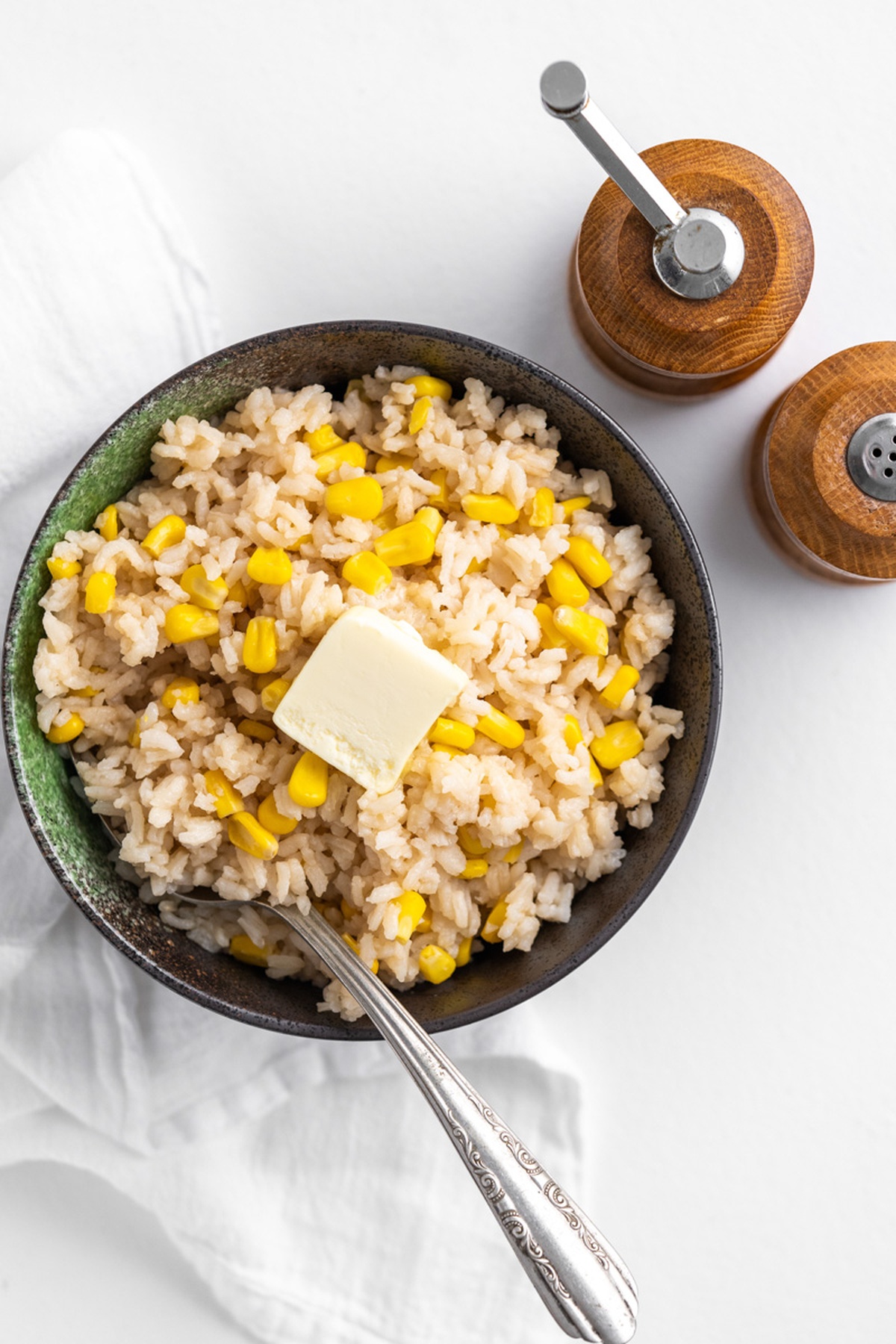 A bowl with Corn Rice and a pat of butter.