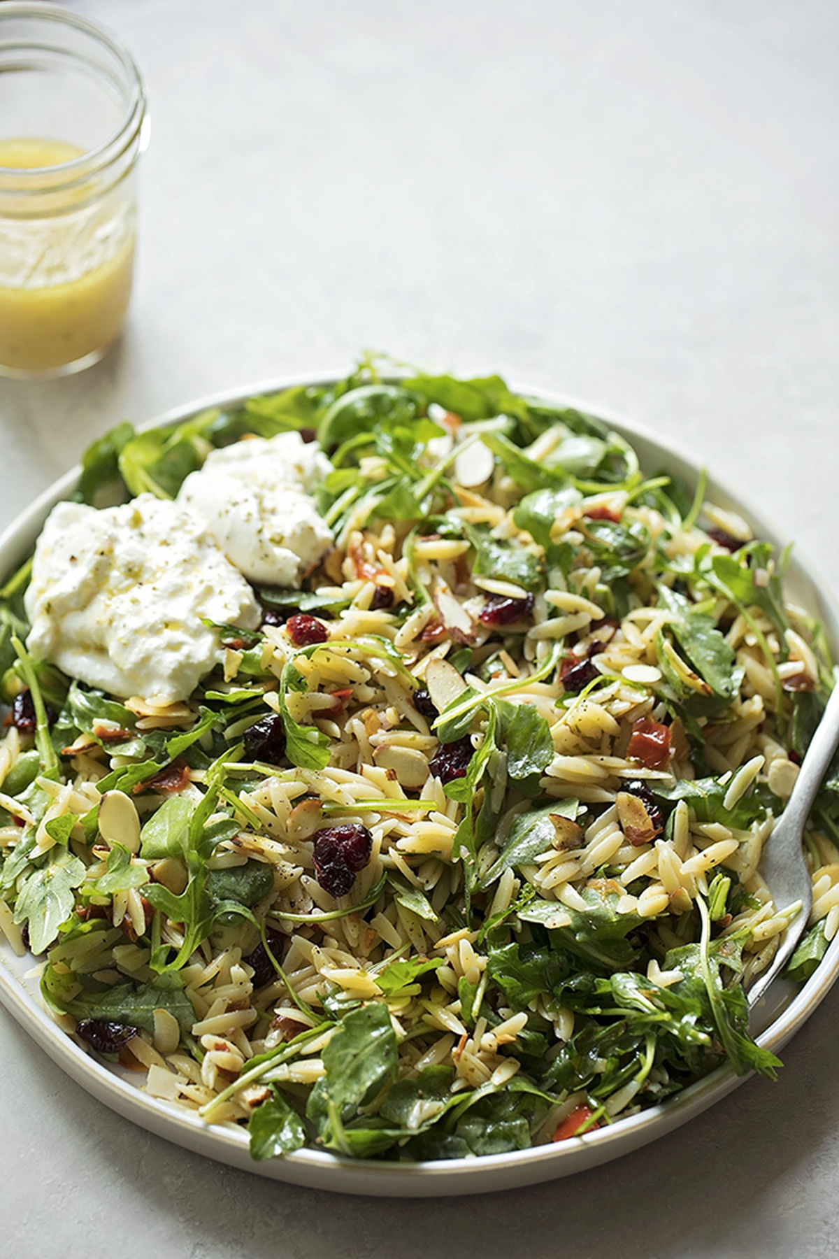 A round, salad plate with orzo salad.
