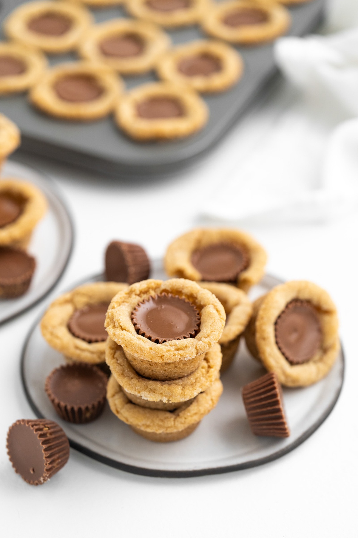 A gray plate with piled Reese's Cookies.