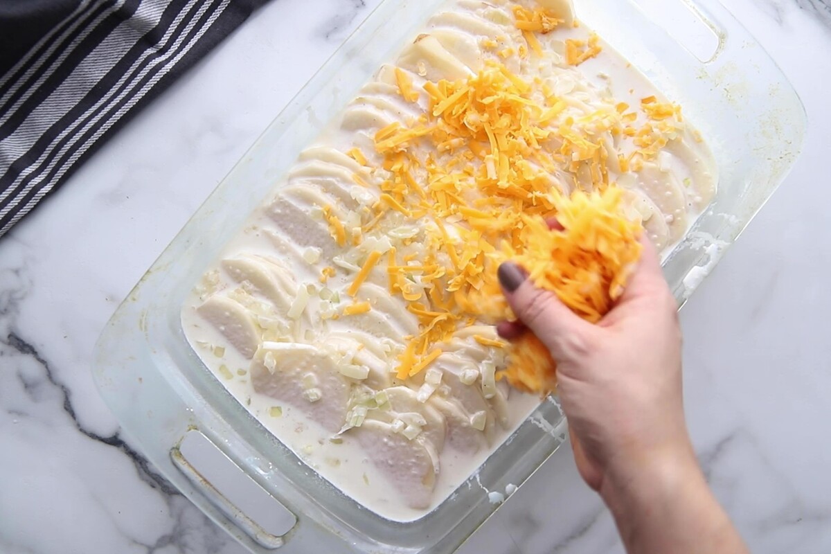 Sprinkling cheese over the top of the potatoes.