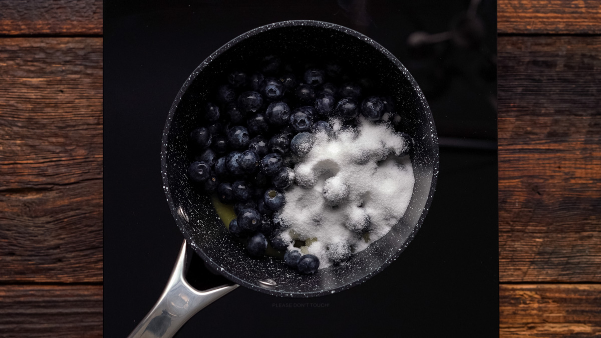 Blueberries and sugar cooking in a saucepan.