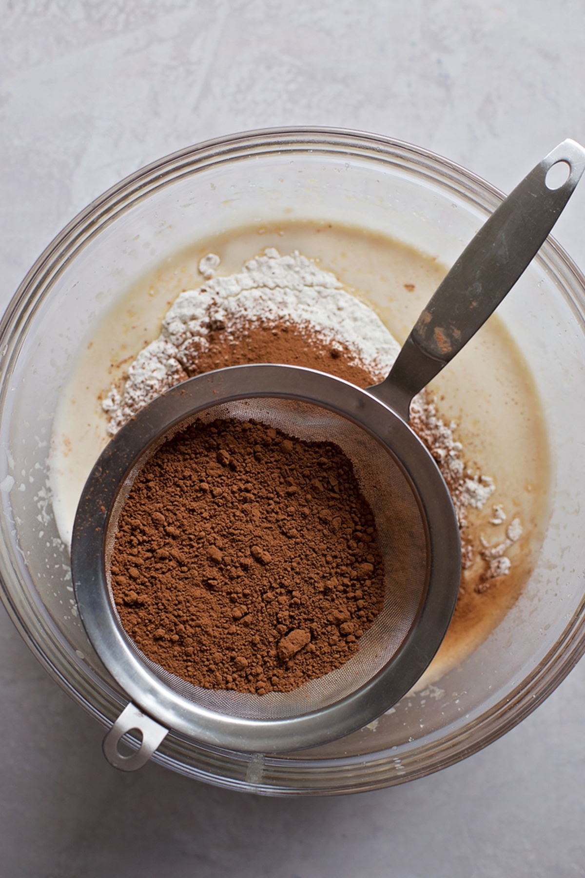 Sifting the dry ingredients using a fine sieve.