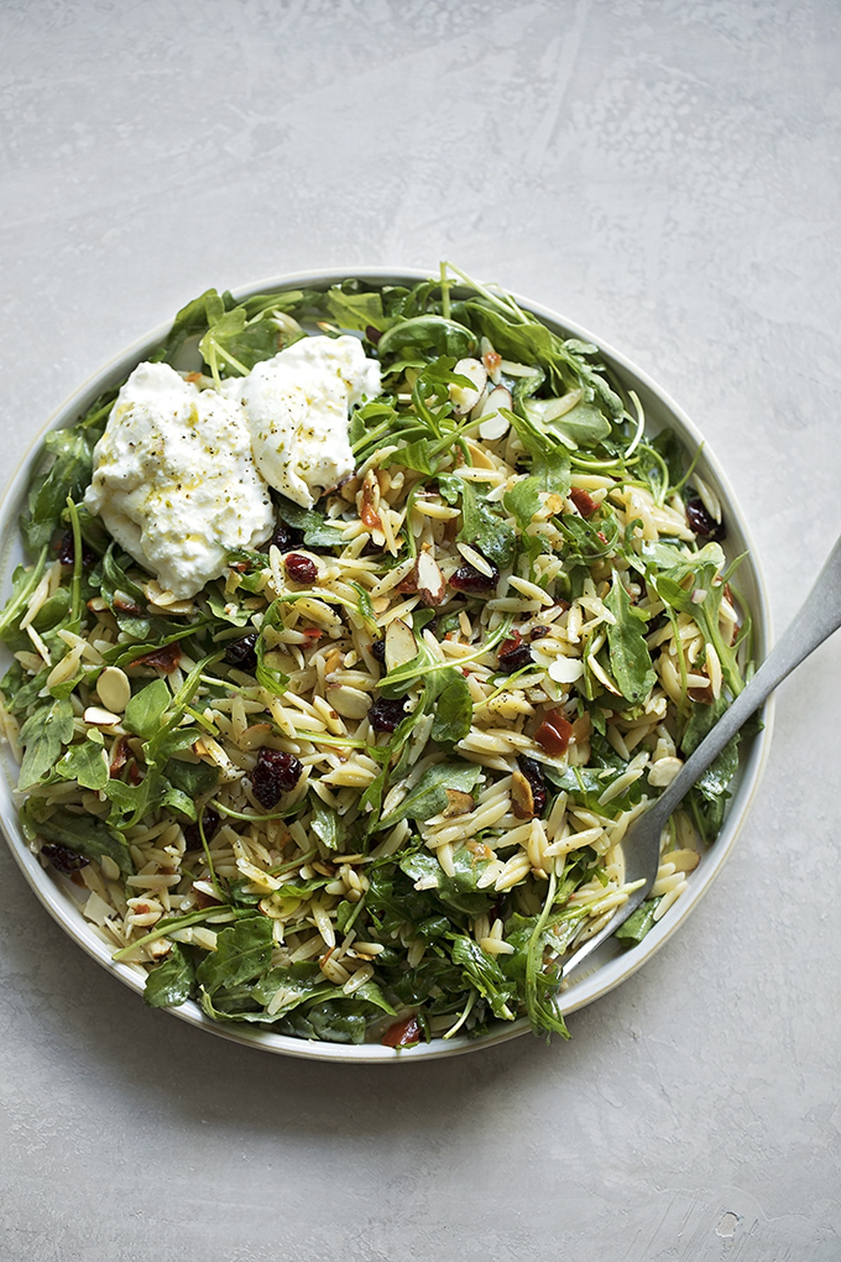 A serving bowl filled with a freshly prepared orzo and arugula salad.