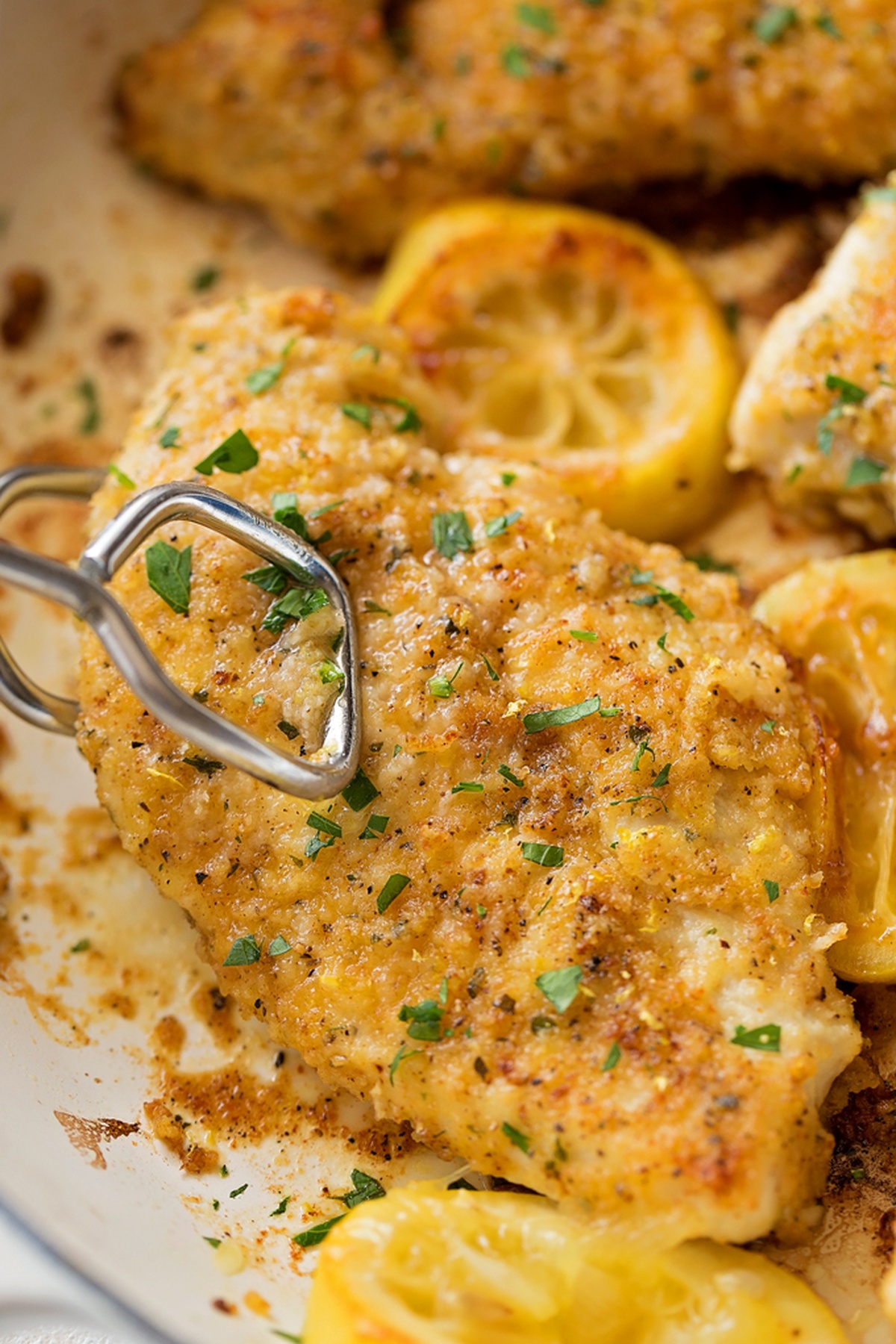 Lemon Pepper Chicken in a dish with lemon and parsley.