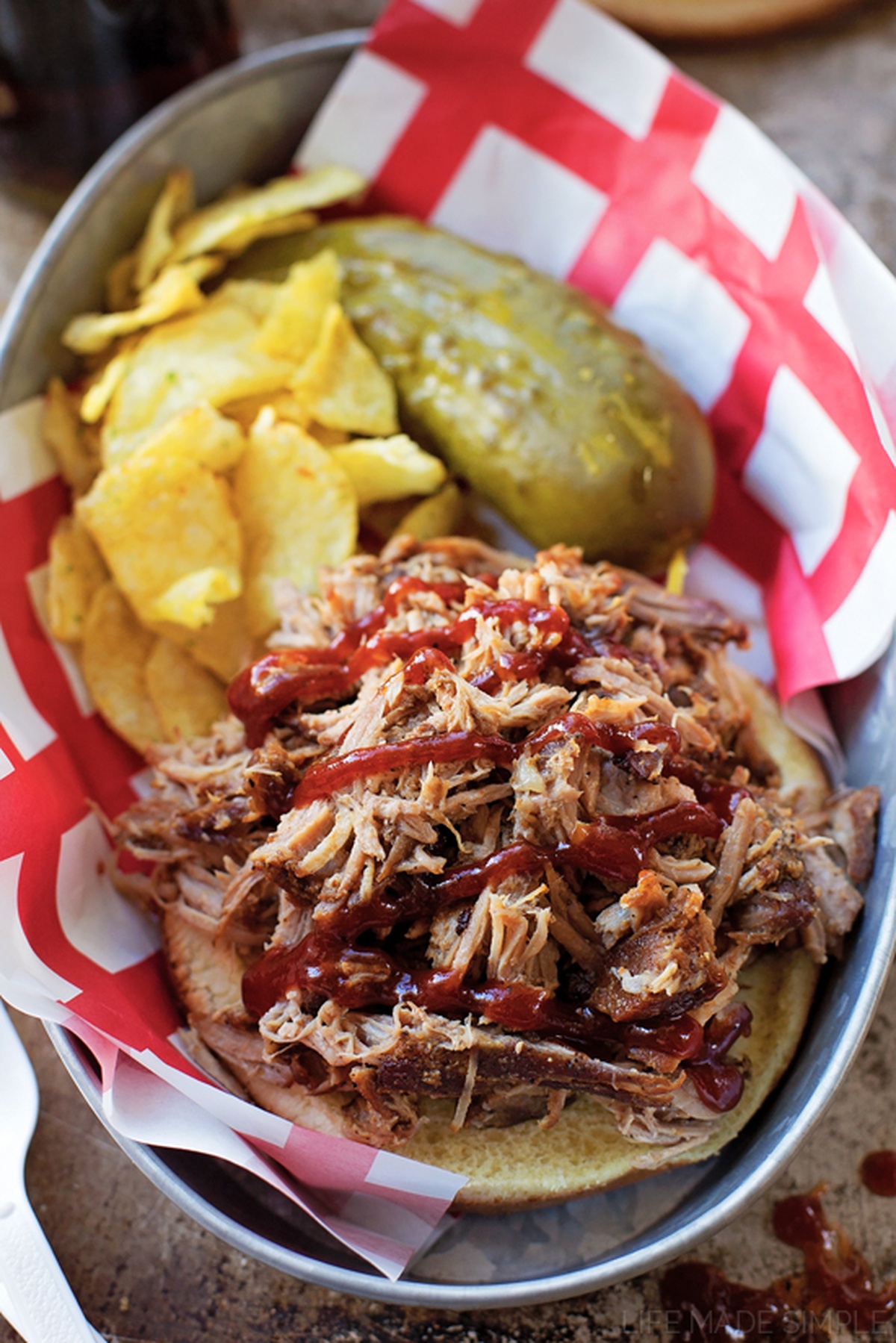 Pulled pork from a Dutch oven on a platter, topped with sauce.