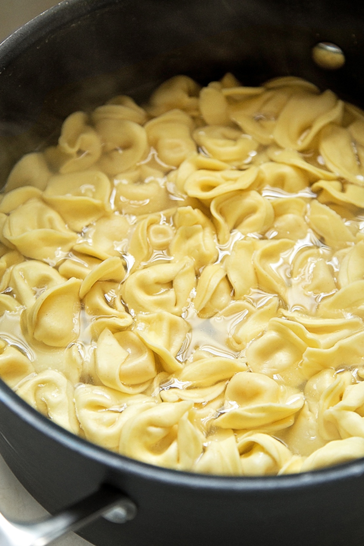 Tortellini cooking in a pot of boiling water.