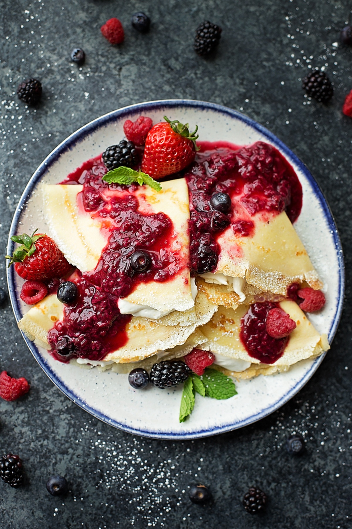 Berry crepes with a generous layer of berry sauce and cream.