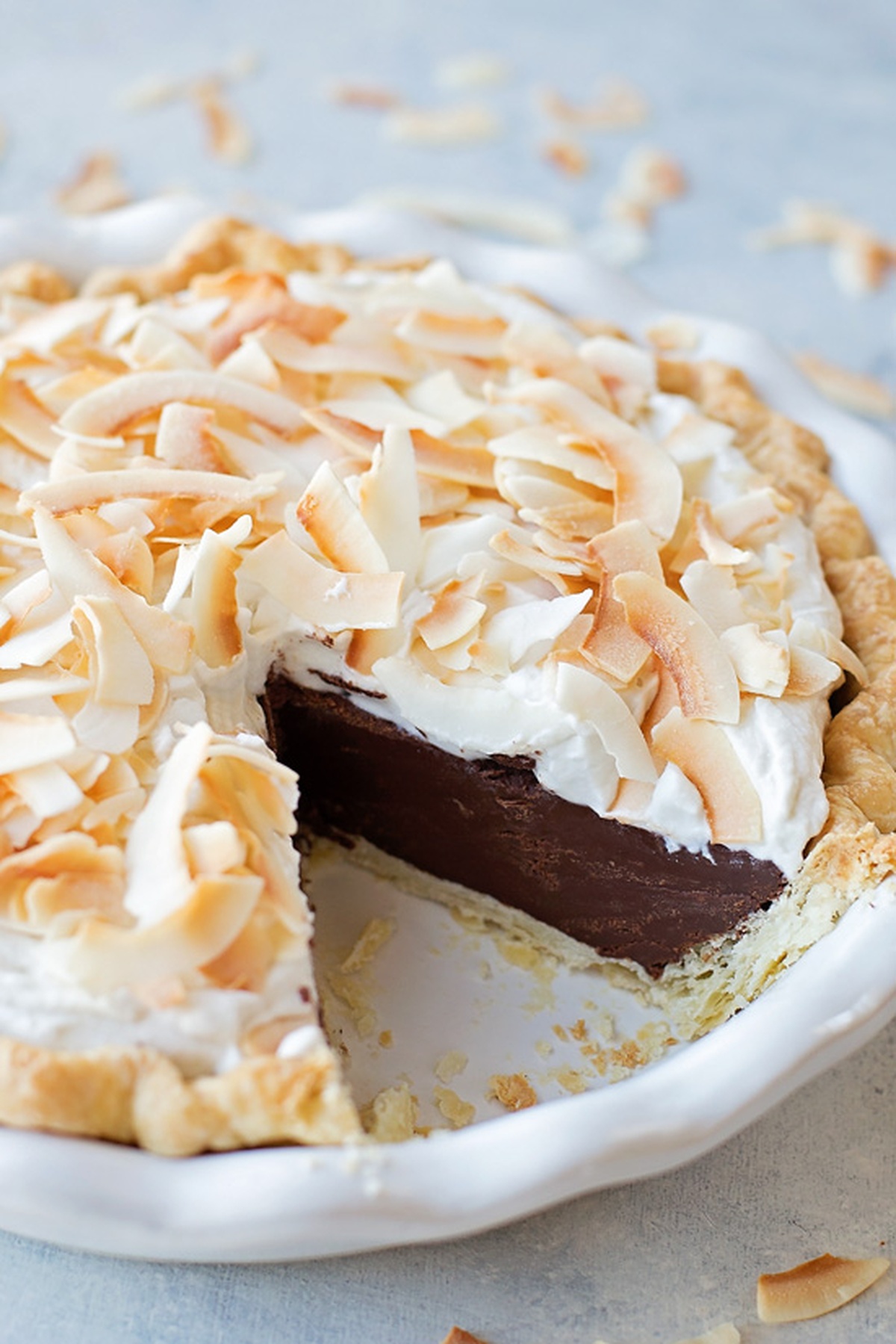 Coconut cream chocolate pie with a slice missing, showing the creamy chocolate filling.