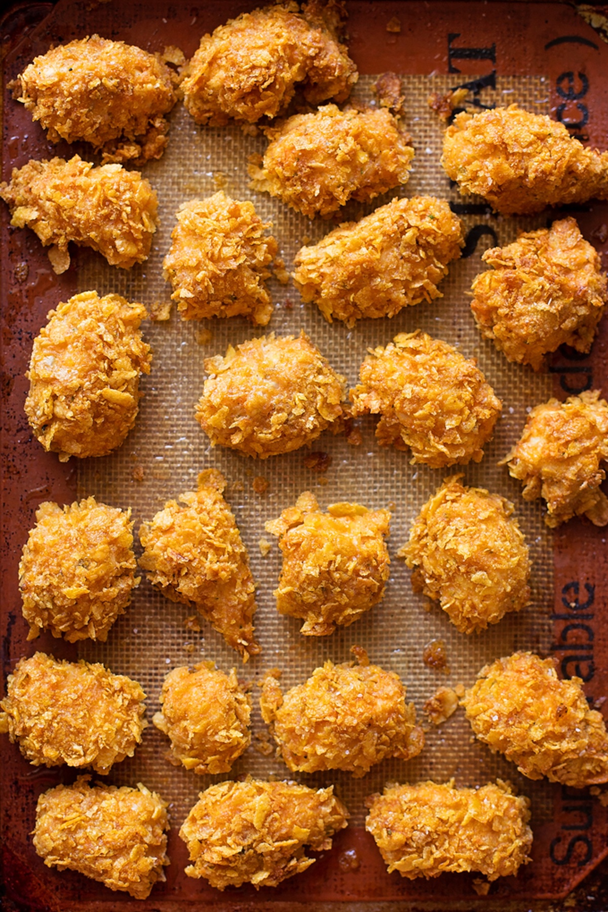 Baked crispy Buffalo chicken nuggets on a baking sheet.