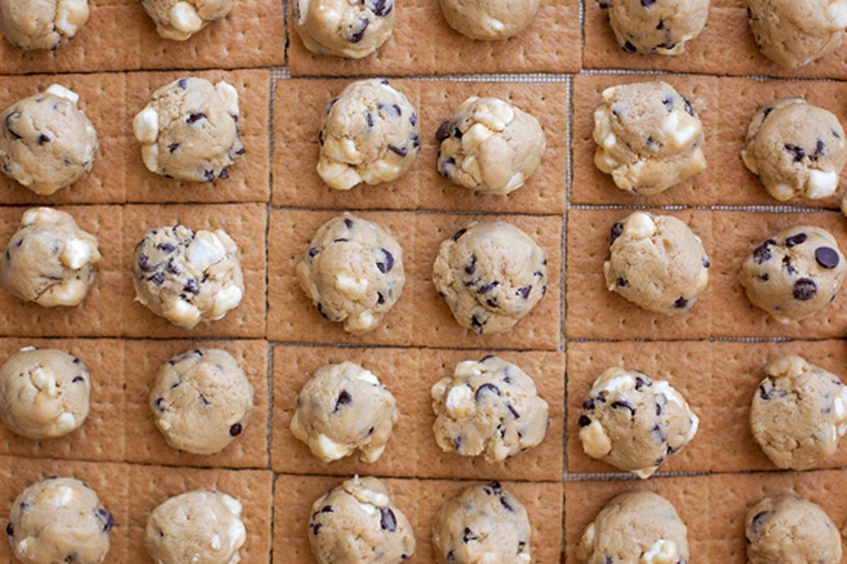 Cookie dough balls with marshmallows and chocolate chips placed on graham crackers.