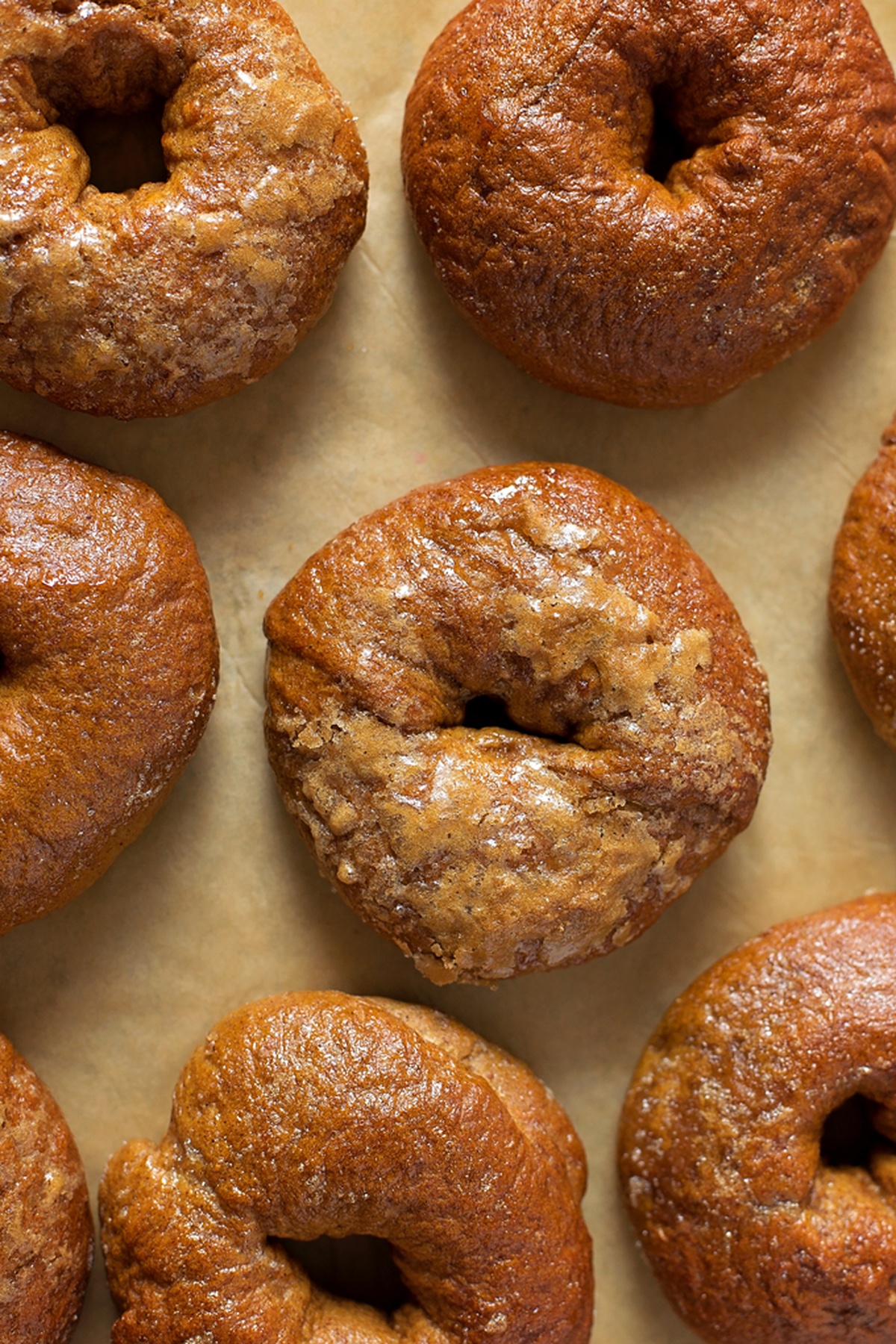 Baked pumpkin bagels cooling on parchment paper.