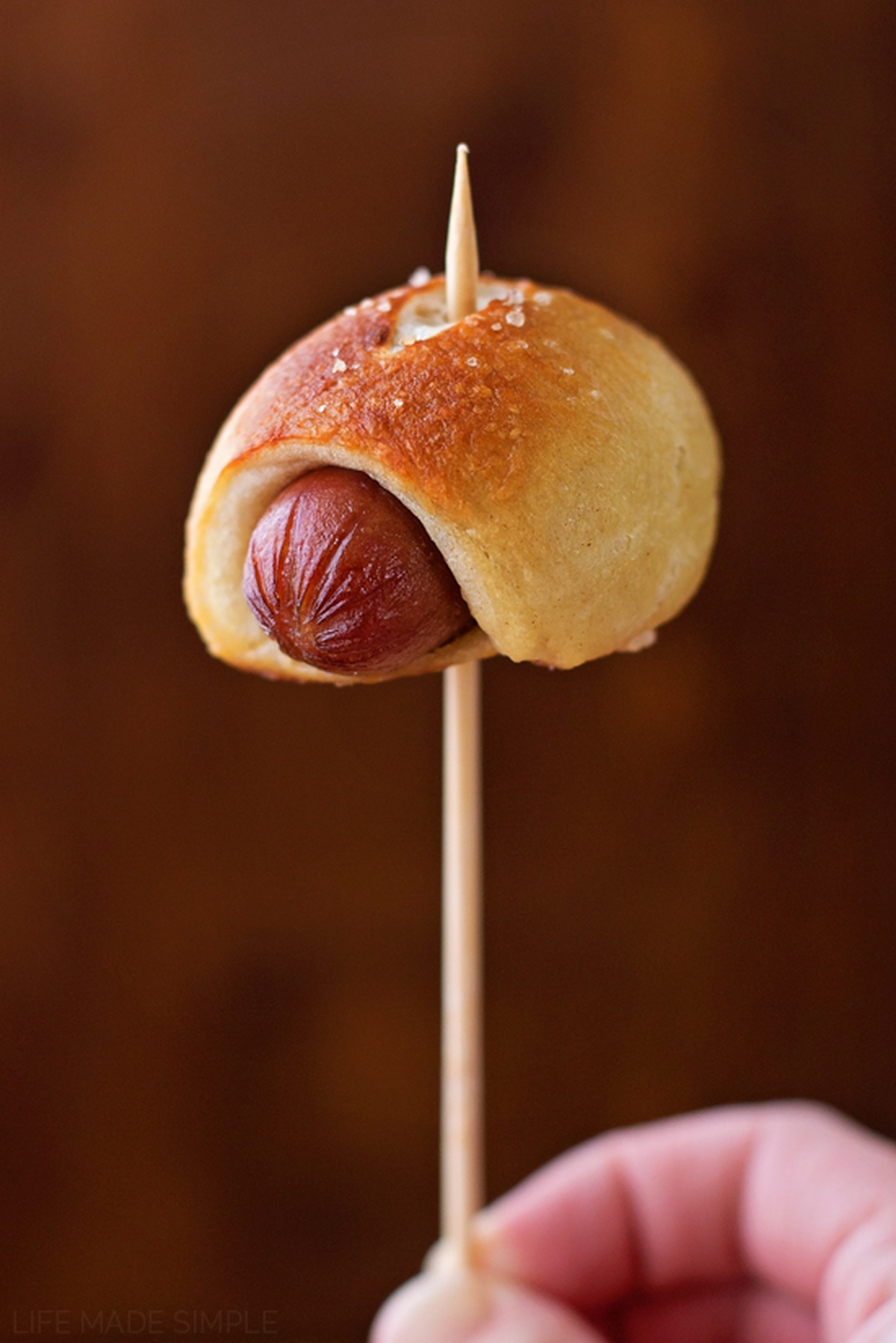 A single mini pretzel dog on a skewer.