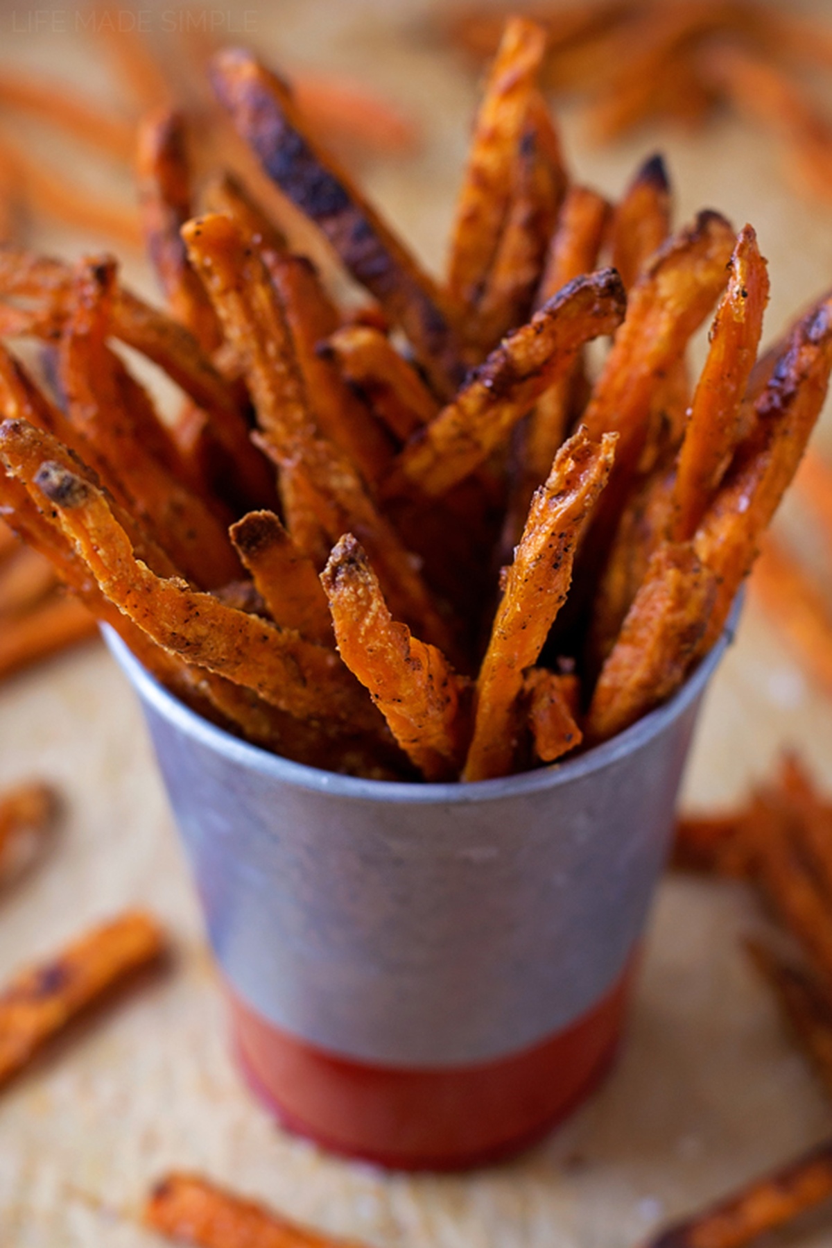 Baked sweet potato fries in a metal cup with a ketchup base.