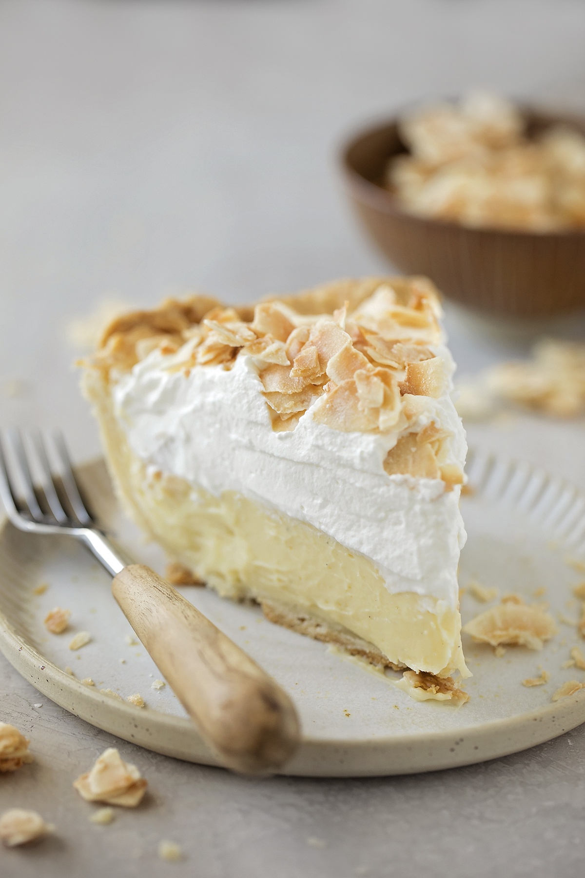 A slice of coconut cream pie on a plate with a fork.