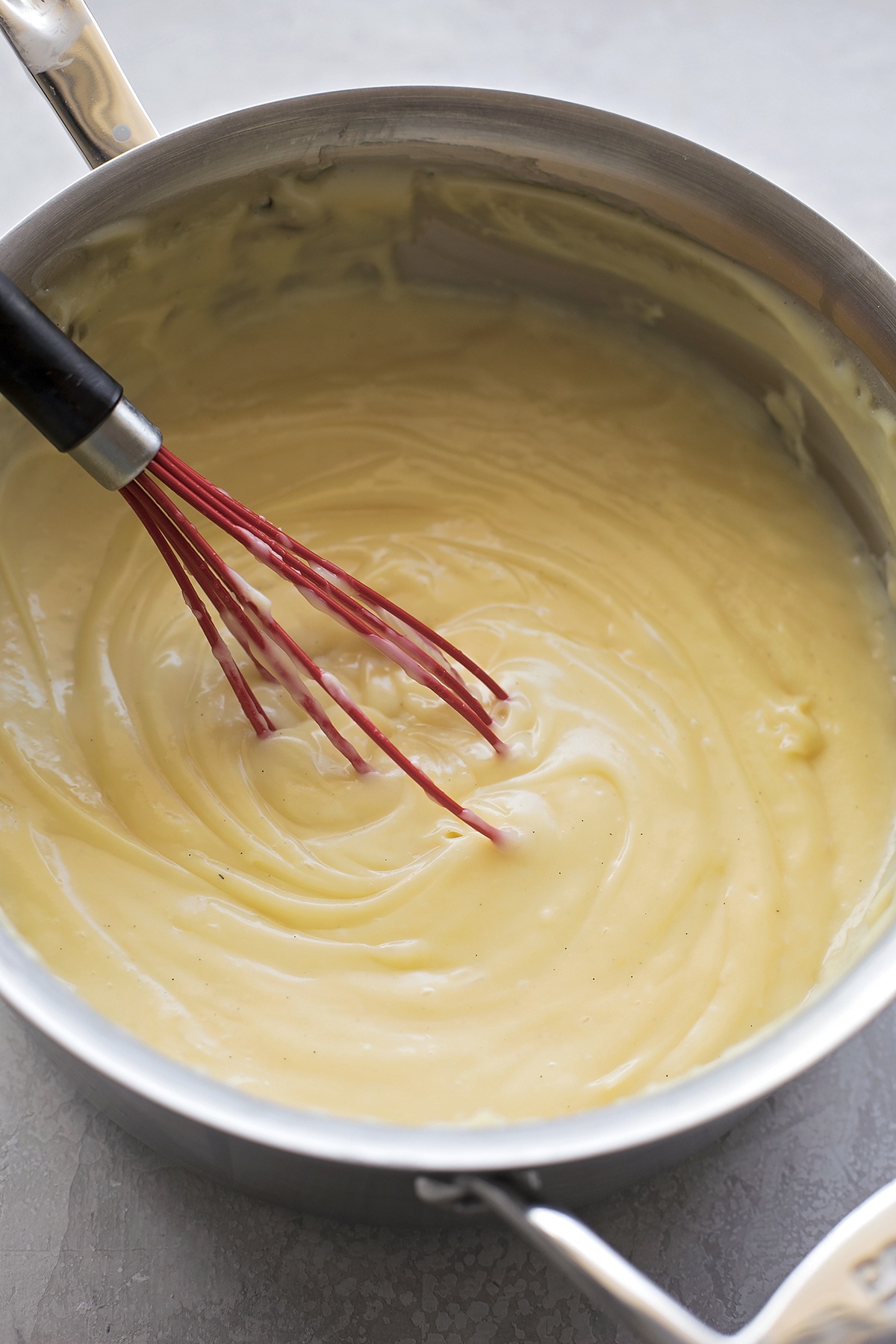 Thickened custard being whisked in a saucepan.