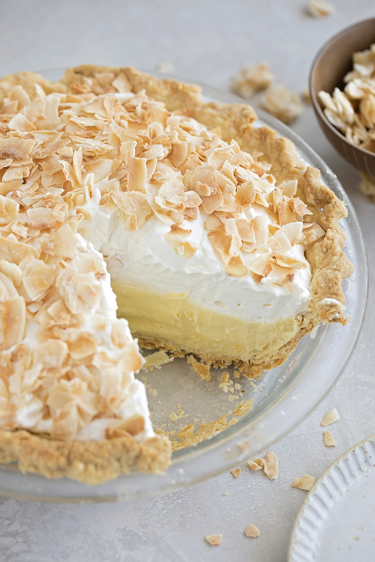 Coconut cream pie with a slice missing, showing the creamy filling.