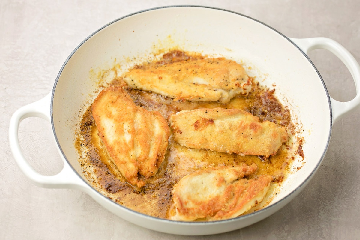 Chicken cutlets browning in skillet.