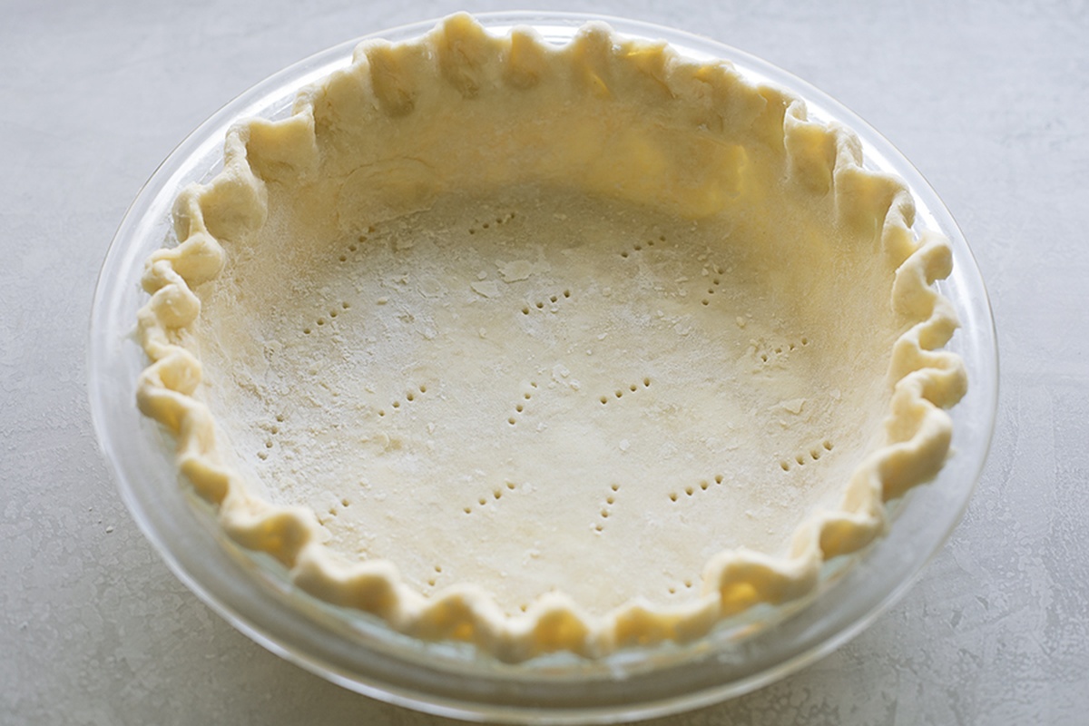 Unbaked pie crust in a clear glass pie dish.