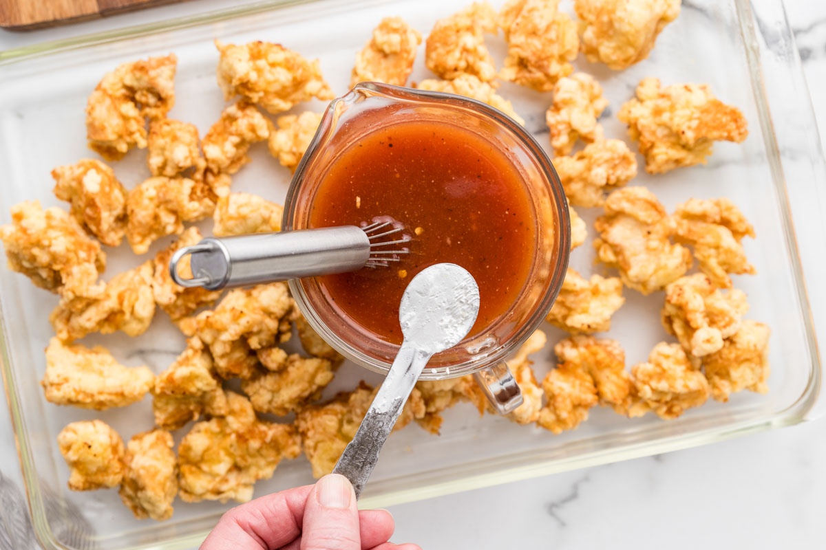 Pouring cornstarch mixture into sweet and sour sauce.