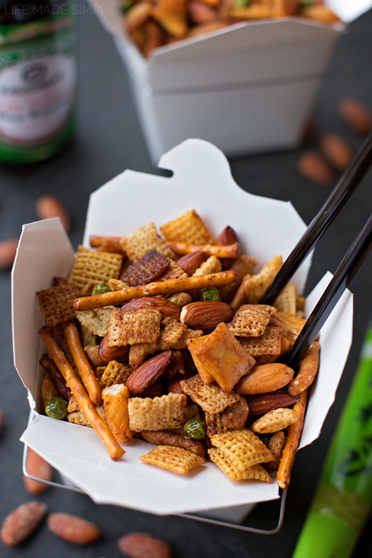 Asian trail mix served in a white takeout box with chopsticks.