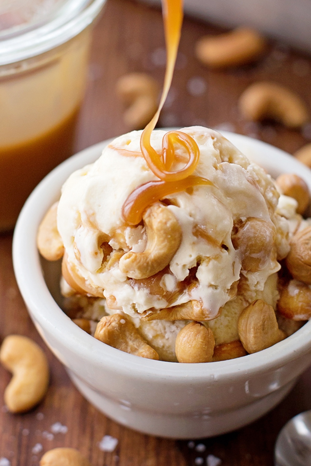 A drizzle of caramel sauce over a bowl of salted caramel cashew ice cream.