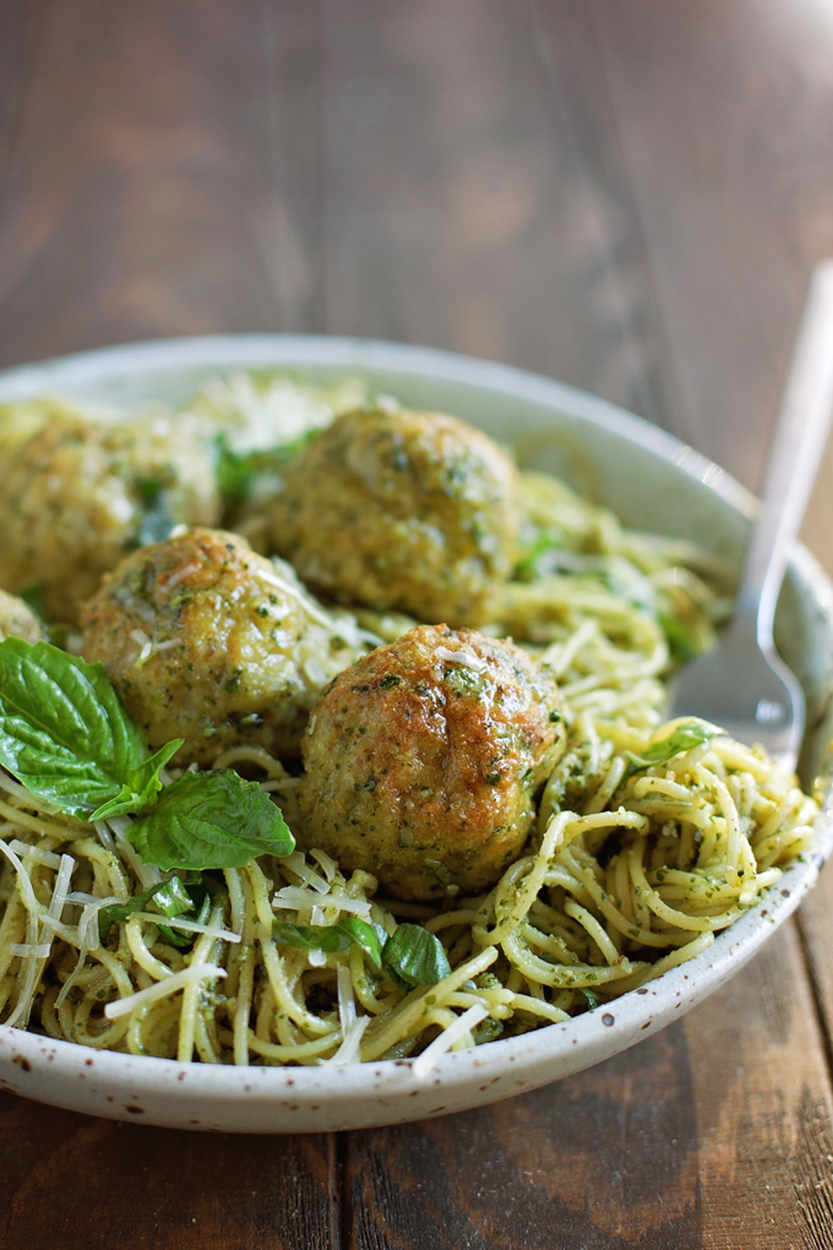 A plate of pesto chicken meatballs served over spaghetti.