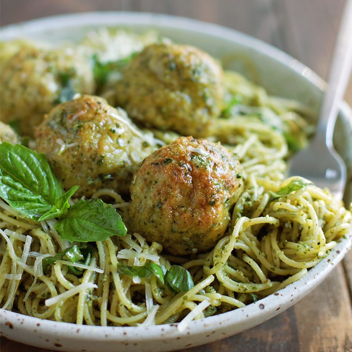 Freshly baked chicken pesto meatballs on a baking sheet.