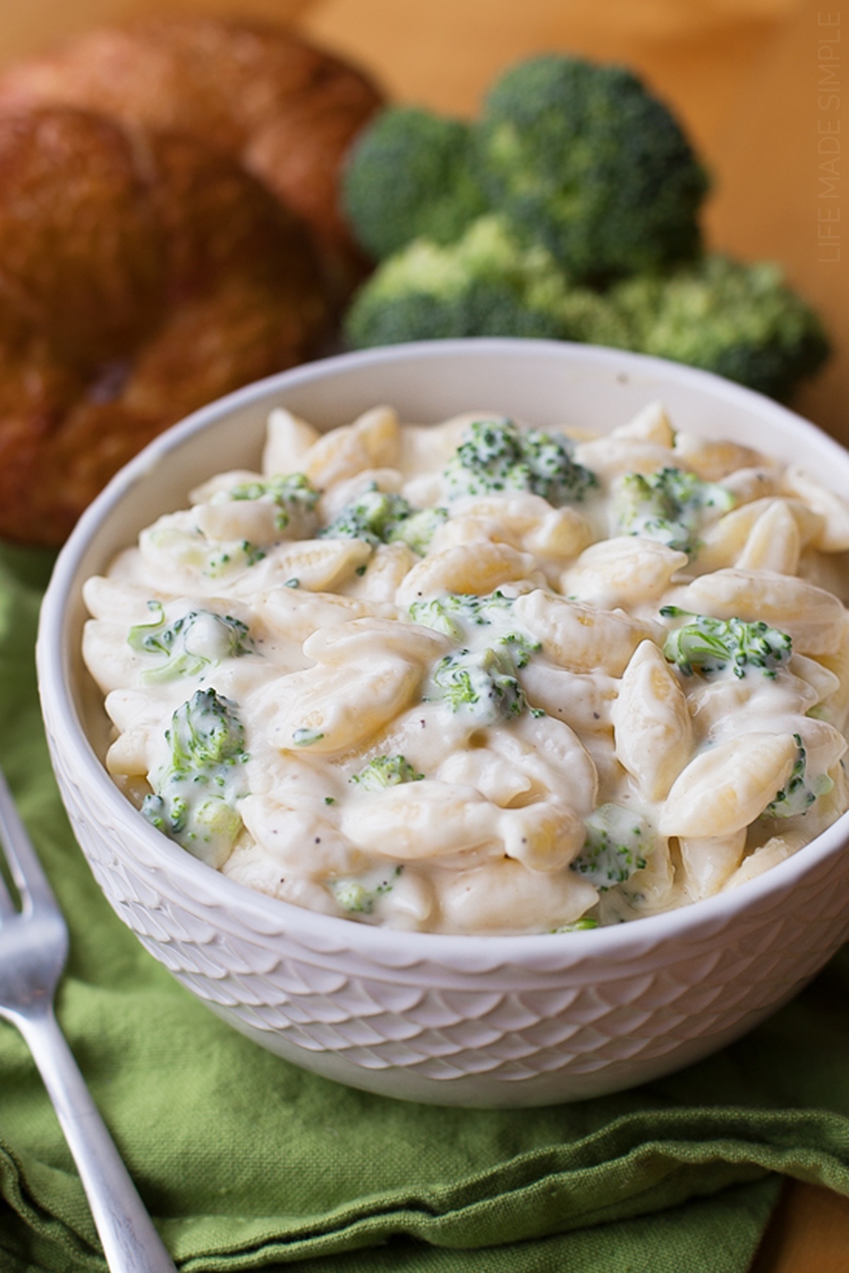 A bowl of white cheddar broccoli shells pasta served with broccoli florets and cheese sauce.