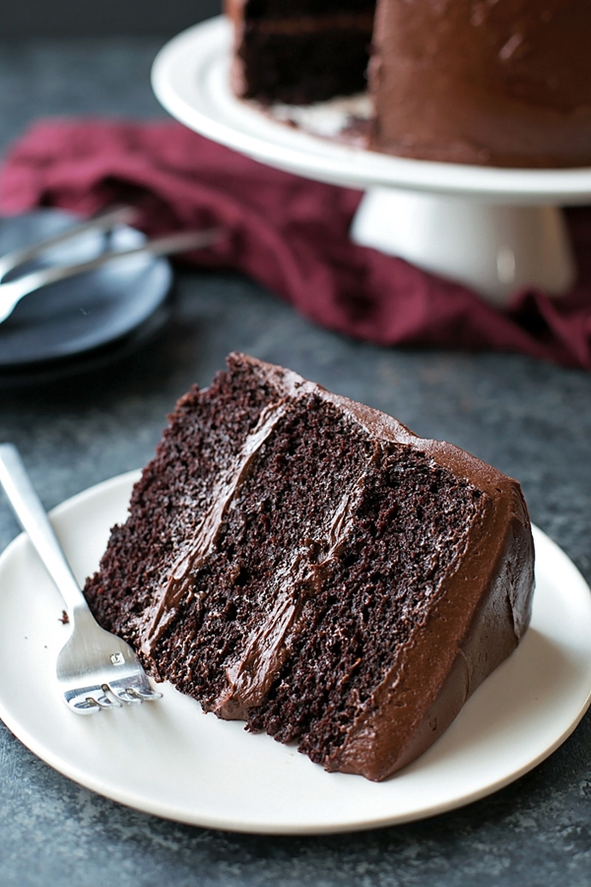 A thick double chocolate blackout cake on a white plate with a fork. 