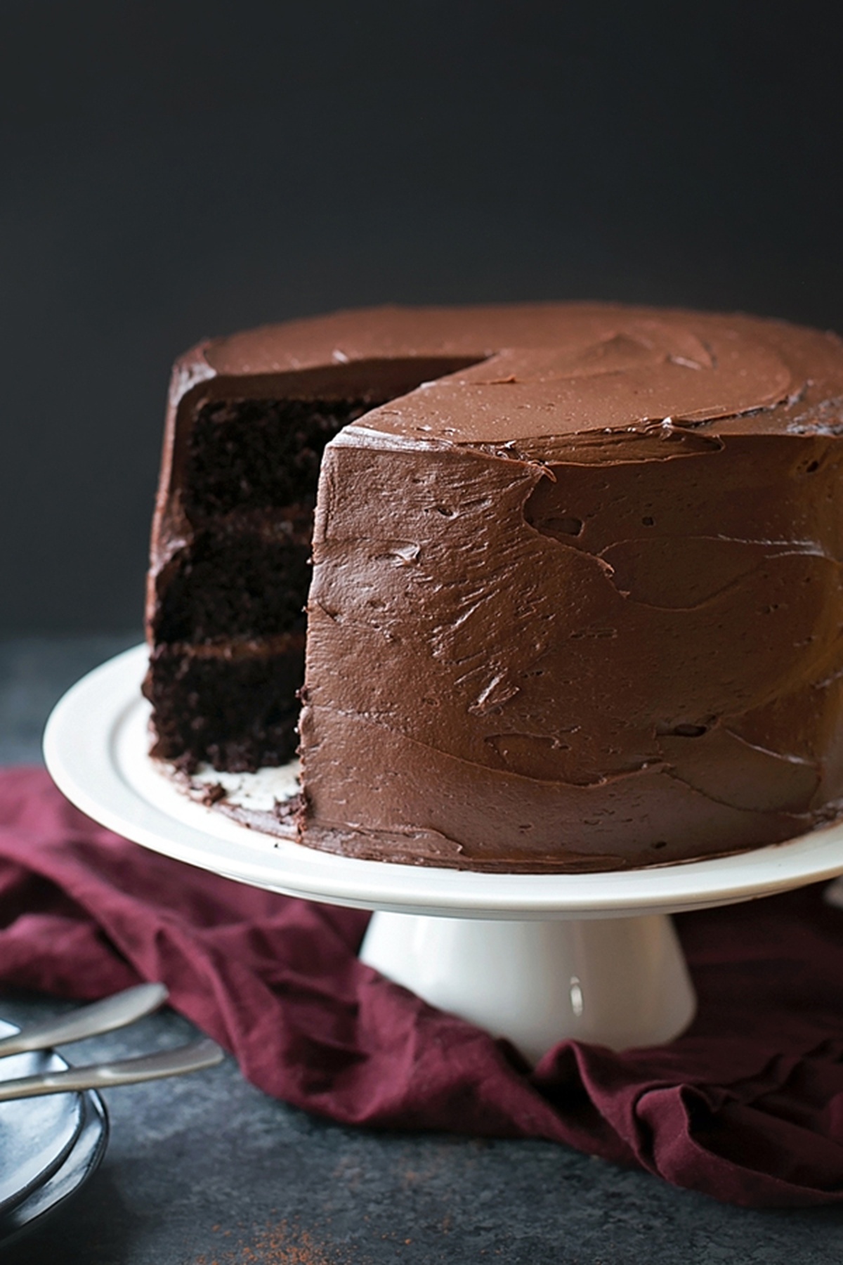 A sliced double chocolate blackout cake on a white stand.