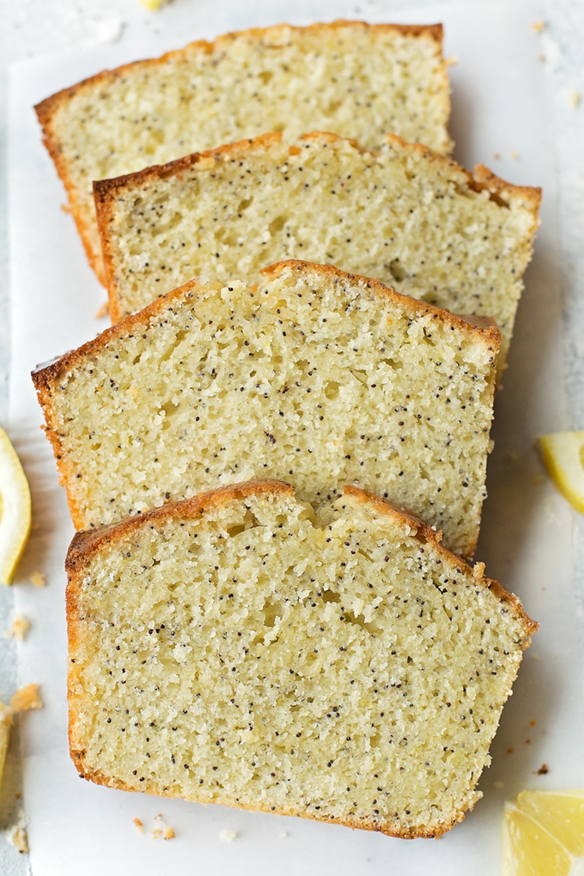 Several slices of lemon poppy seed bread arranged on a white surface.
