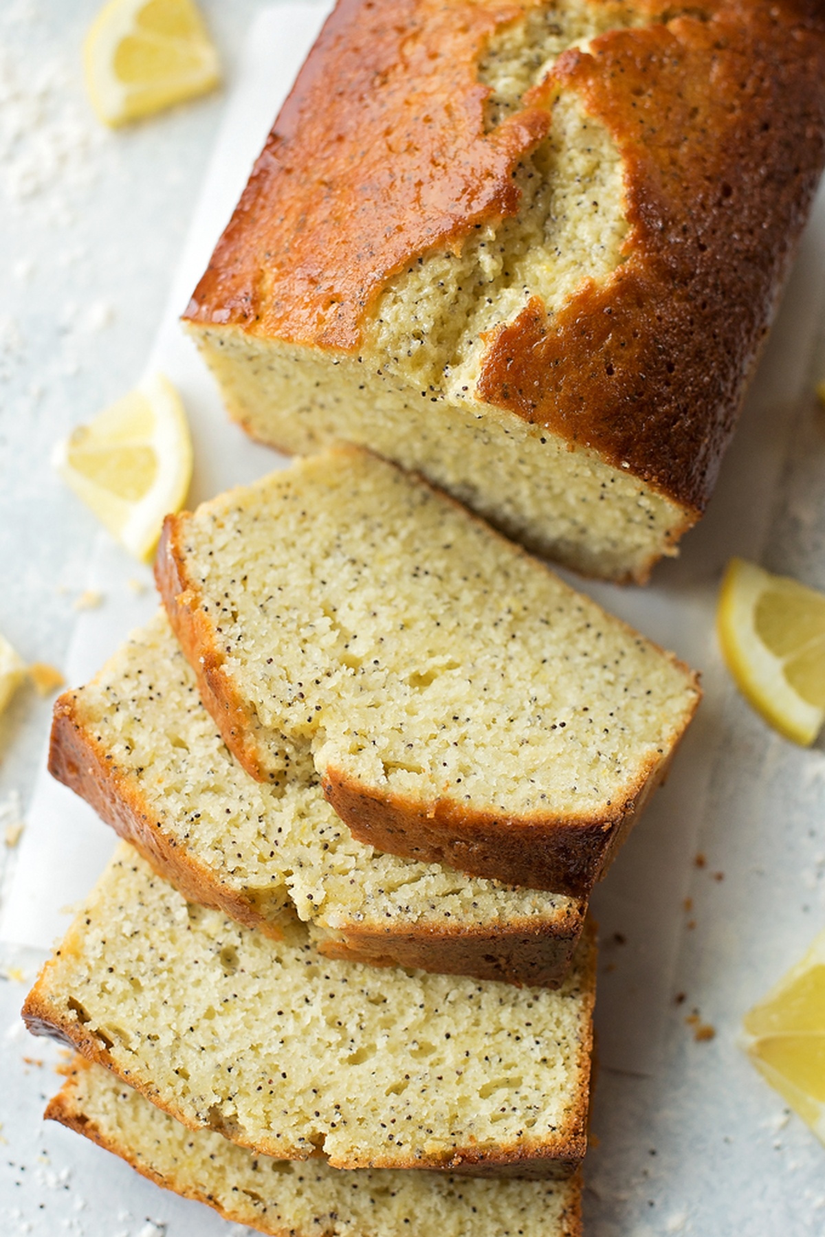 A whole lemon poppy seed bread with slices partially cut.
