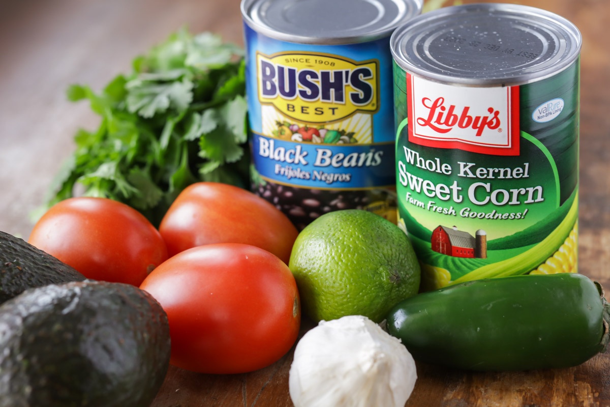 Ingredients for Black Bean and Corn Salsa on a wooden surface.