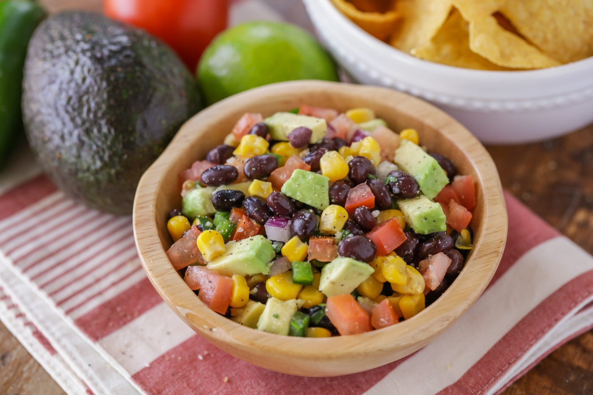 A wooden bowl of corn avocado black bean salsa.