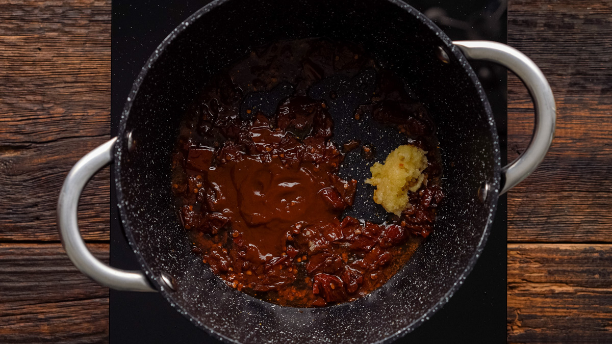 Garlic and adobo sauce added to the saucepan.