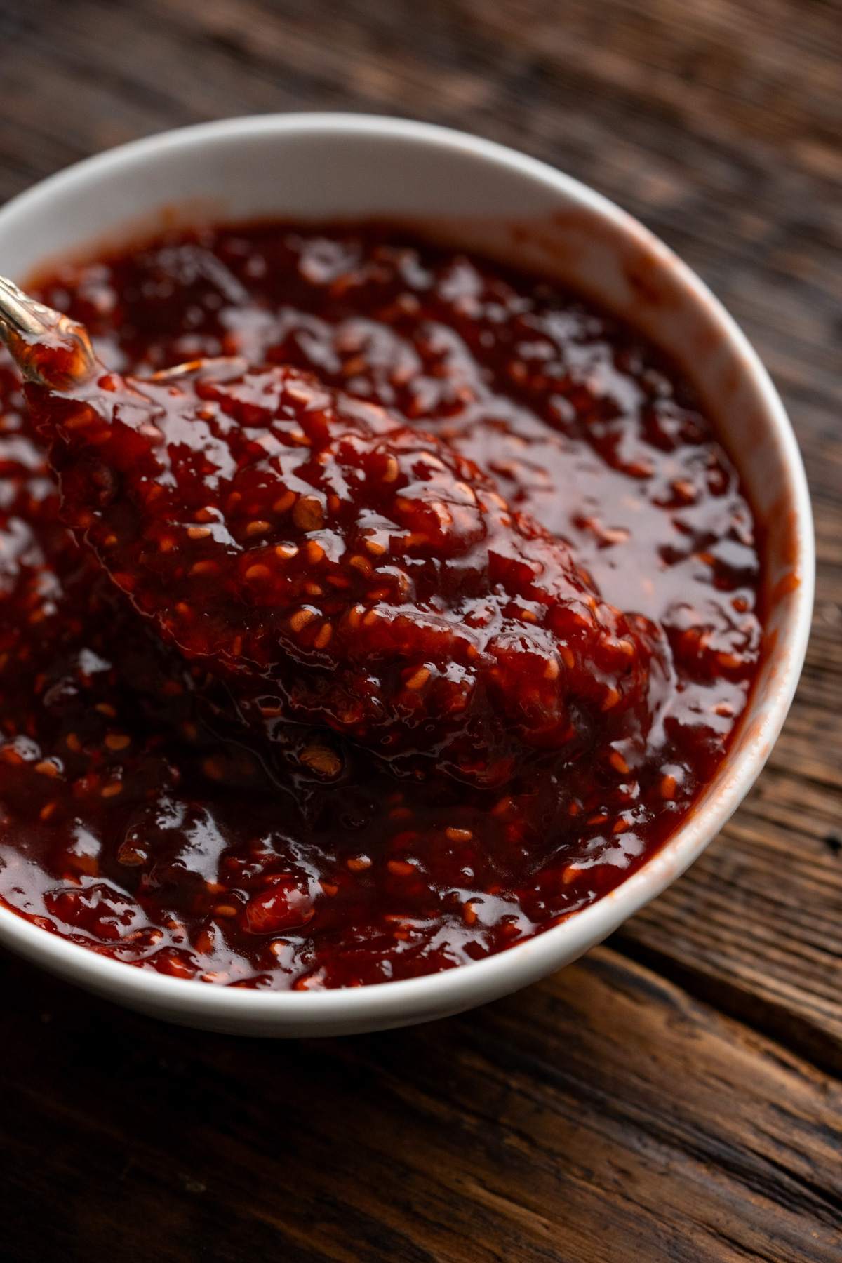 Bowl of raspberry chipotle sauce with a spoon lifting out some sauce.