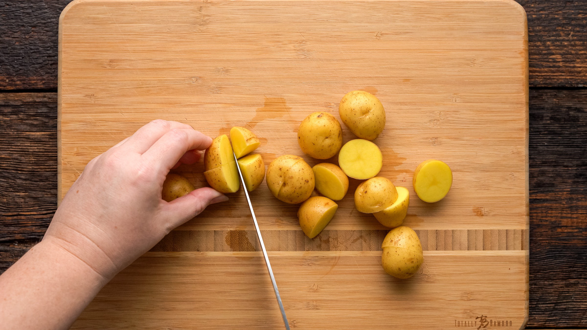 Potatoes being chopped on a cutting board.