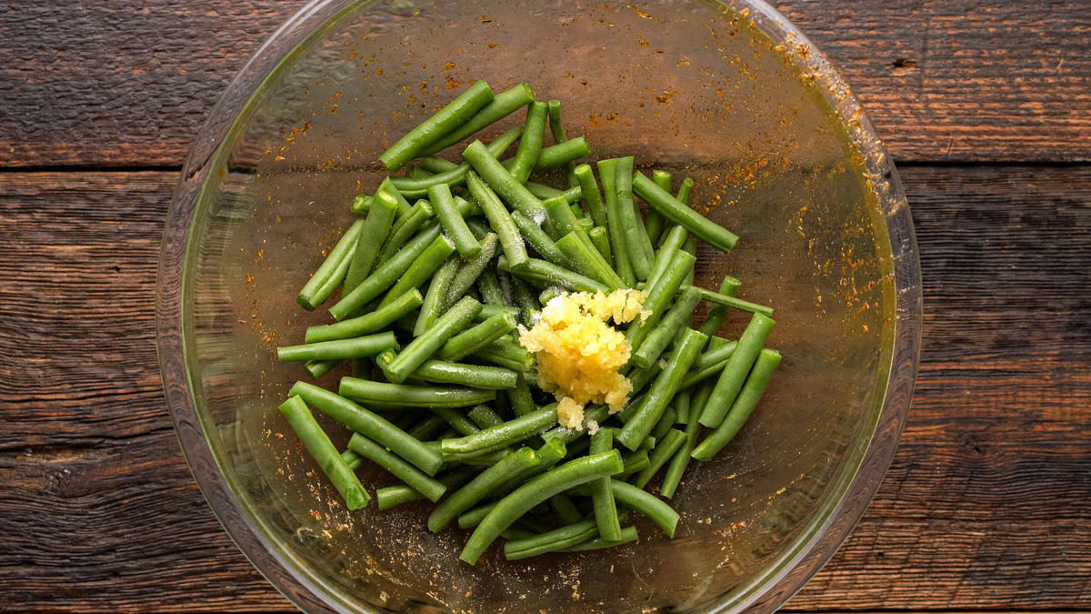 Green beans and garlic added into a glass bowl.