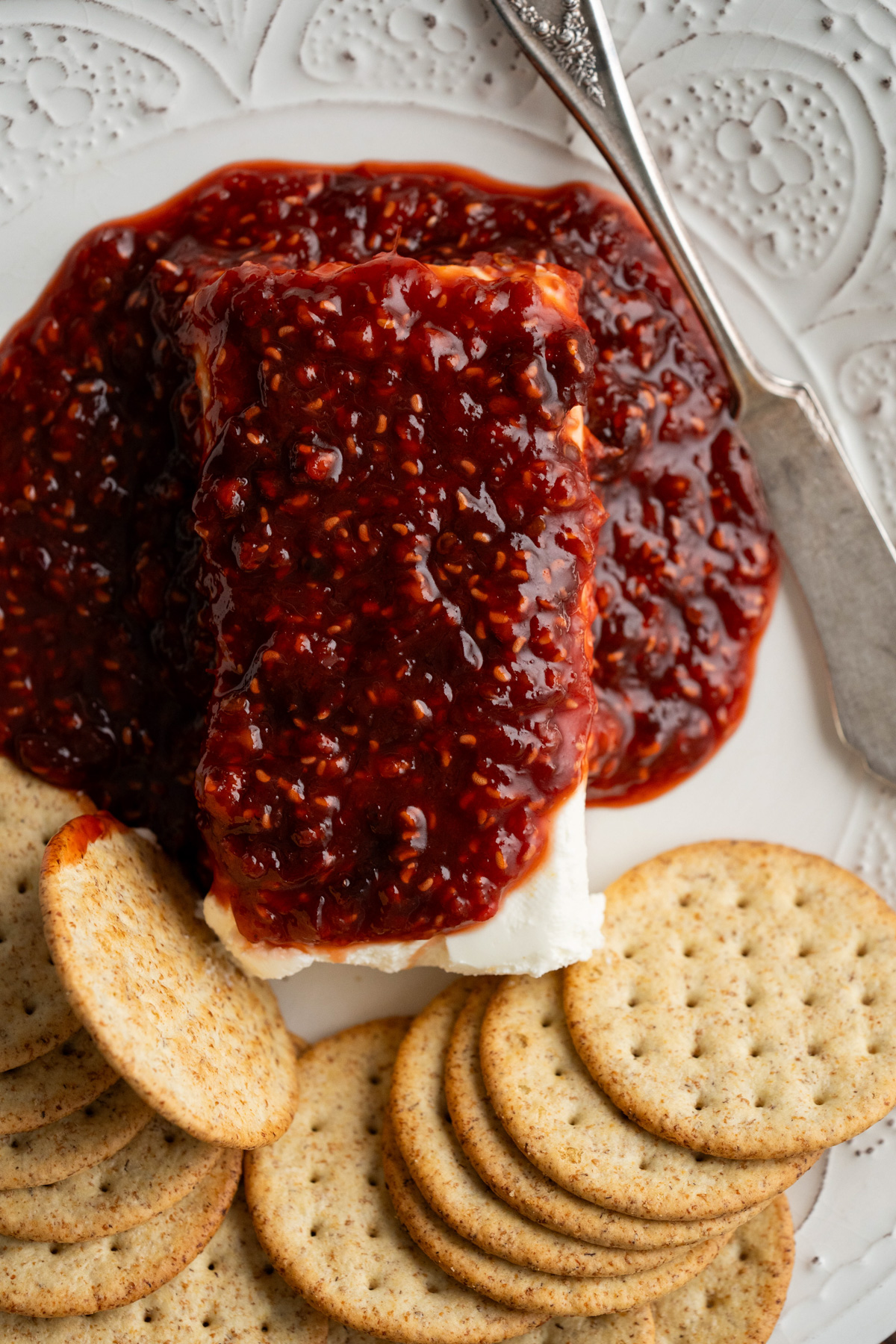 Raspberry chipotle cream cheese dip on a white plate with crackers. 