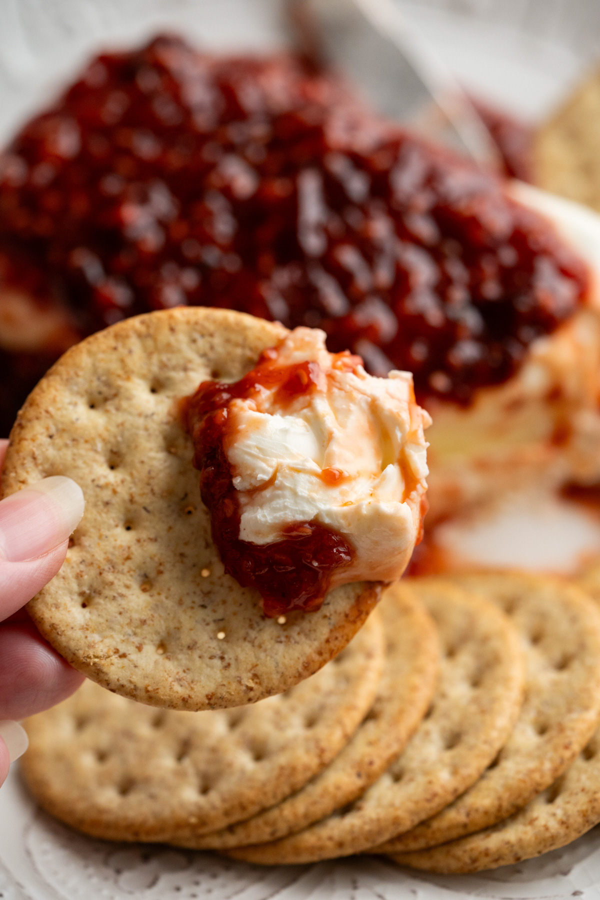 A cracker with raspberry chipotle cream cheese dip on it.