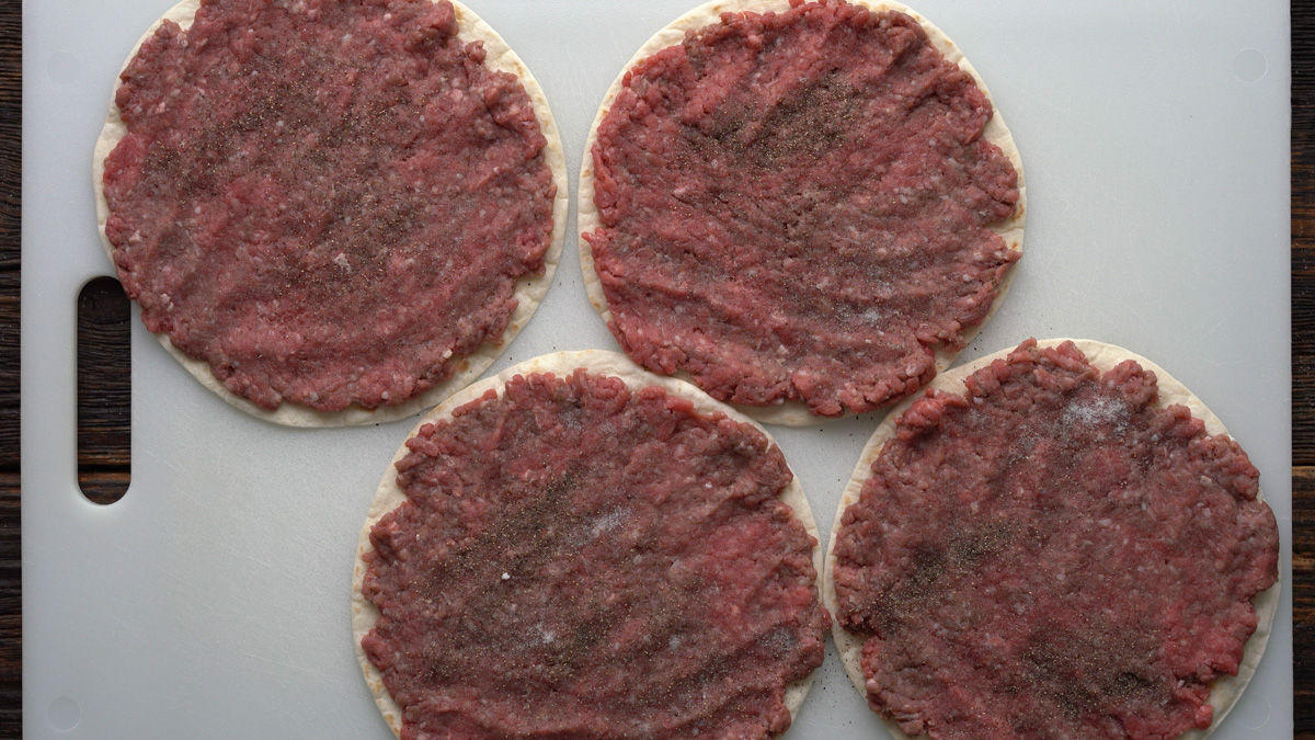 Ground beef pressed onto a flour tortilla.