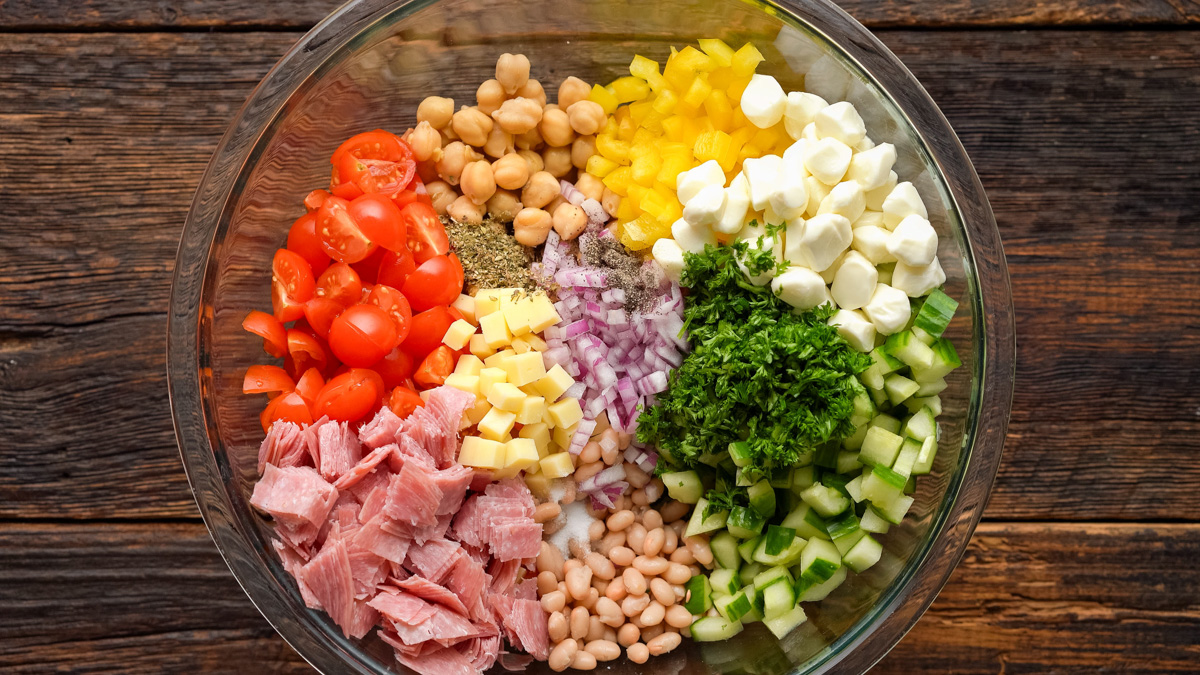 Ingredients for dense bean salad in a glass bowl.
