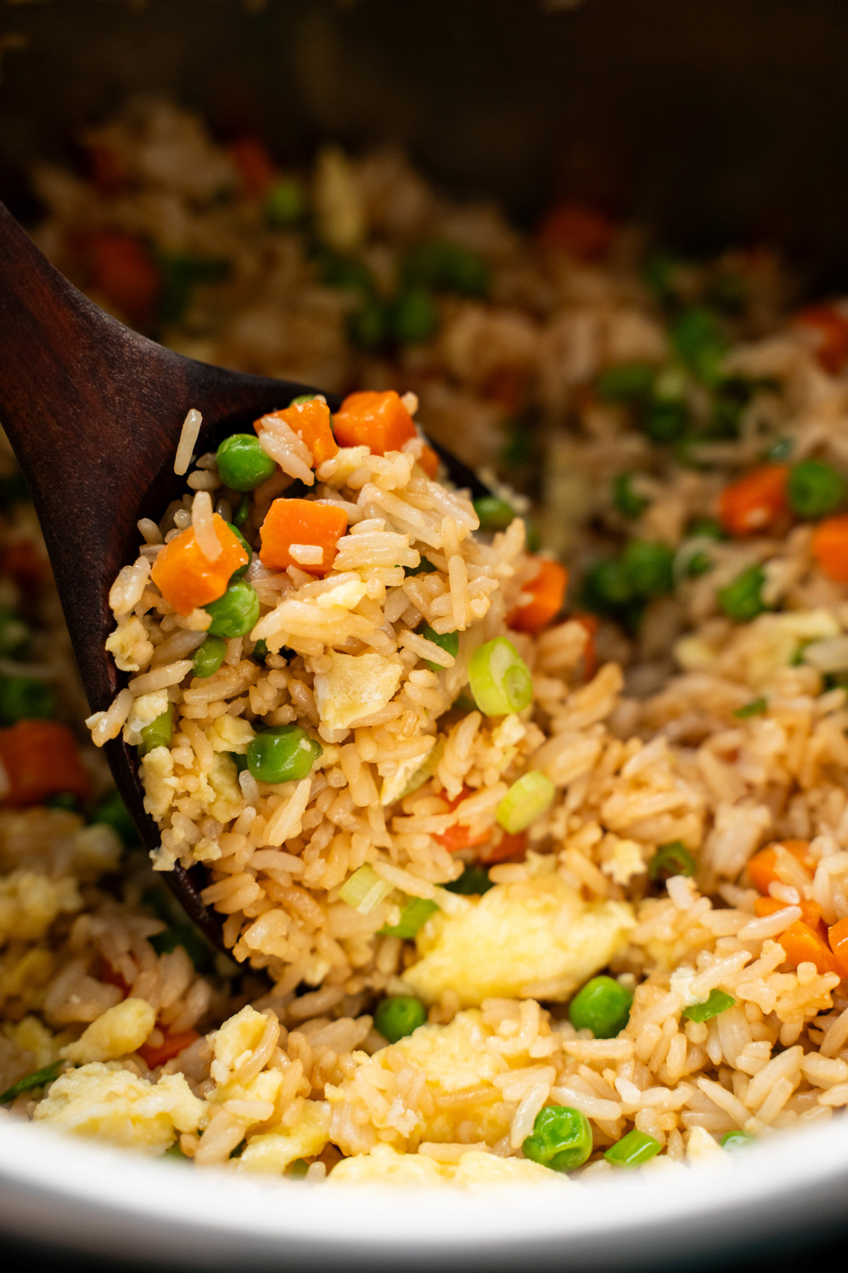 Wooden spoon filled with fried rice.